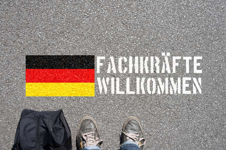 A man with the suitcase, german flag and slogan skilled workers welcomeの写真素材