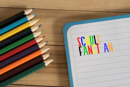 Colorful pencils and a booklet with the text School begins