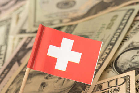 Flag of Switzerland and dollar bills in the background