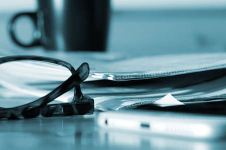 A newspaper, reading glasses and a smartphone
