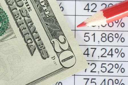 One dollar bill in front of a spreadsheet with numbers and percent
