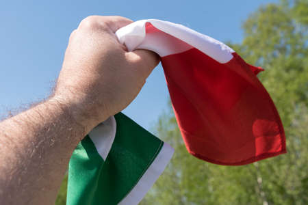 A man holds the national flag of Italy in his handの写真素材