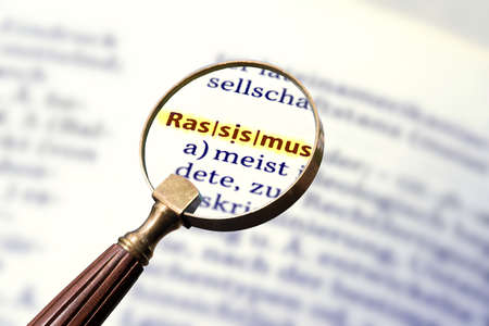 A magnifying glass, dictionary and explanation for the term racismの写真素材
