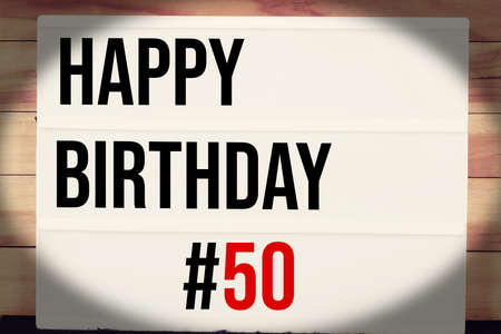 Happy Birthday 50 text on lightbox on wood background. Happy birthday 50 concept