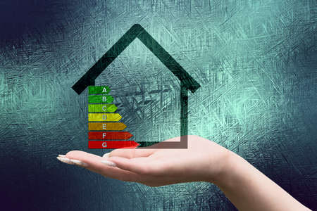 Energy efficiency concept with house and energy efficiency chart in hand on grunge backgroundの写真素材