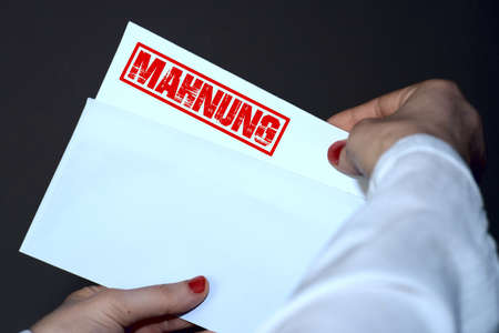 Close-up of a woman's hand holding an envelope with a red stamp