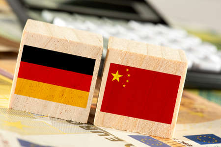 Wooden blocks with flags of Germany and China on the background of a calculator, close-upの写真素材