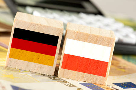 German and Austrian flags on wooden blocks with euro money and calculator background.の写真素材