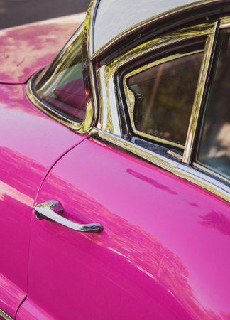Close-up of the front door of a pink vintage car.
