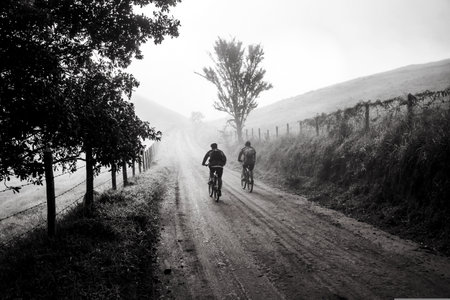 Cyclists on a dirt road in the misty morning.の写真素材