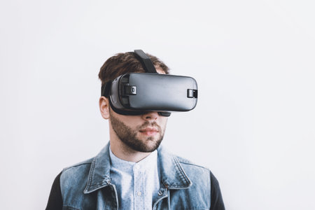 Young man wearing virtual reality goggles over white background. Future technology concept