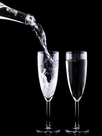 Pouring champagne into two glasses on black background, close-upの写真素材