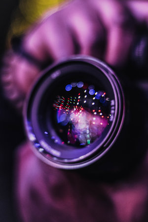 Photographer's hand holding a camera lens with bokeh backgroundの写真素材
