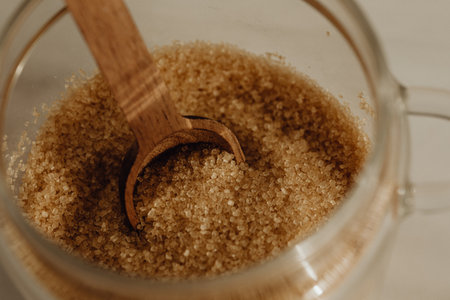 Brown sugar in a glass jar with a wooden spoon. Selective focus.