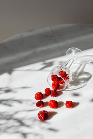 Fresh raspberries in a glass on a white background with shadowsの写真素材