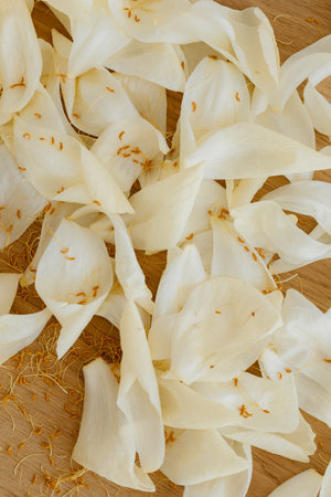 White petals of jasmine on a wooden cutting board.