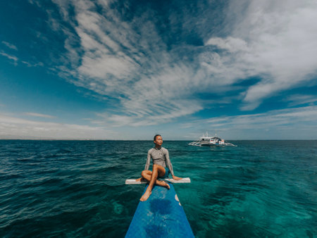 Young woman sitting on a paddle board in the middle of the sea