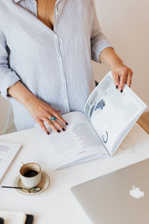 Midsection of pregnant businesswoman reading book at desk in office.
