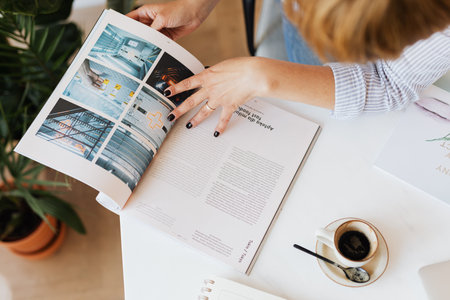 Cropped image of businesswoman reading magazine at workplace in office.の写真素材