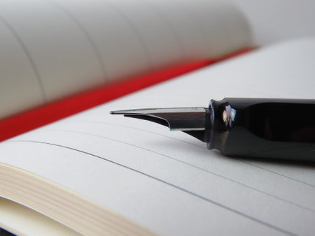 Closeup of a black fountain pen on a notebook with red backgroundの写真素材