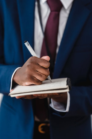 cropped shot of african american businessman holding notebook and penの写真素材