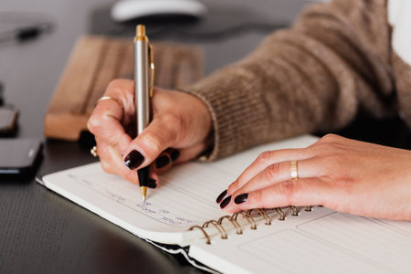 Close up of a business woman writing in a notepad at her desk
