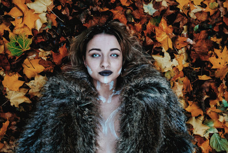 Beautiful young woman in a fur coat with a hood in the autumn leaves