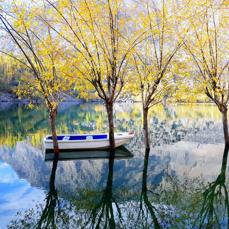 Boat on the lake with reflection of trees in autumn forest.の写真素材