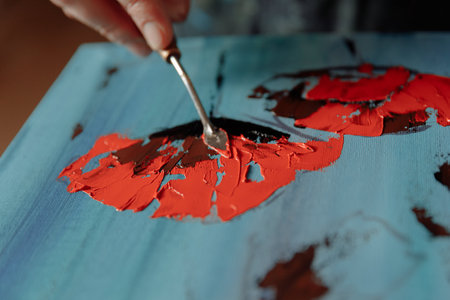 Painting with red paint on a blue wooden table. Close-up.