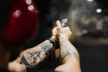 Close-up of tattooed man holding a gun in his handの写真素材