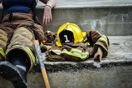 firefighter sitting on stairs with helmet and axe ready to help.の写真素材