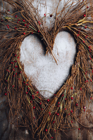 Christmas wreath in the shape of a heart on a wooden backgroundの写真素材