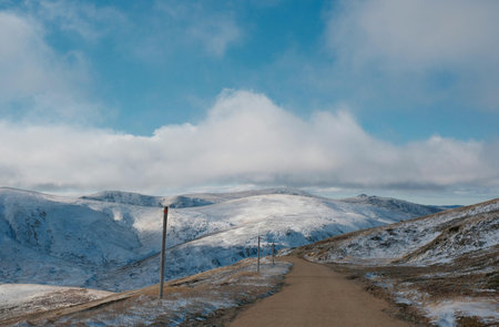 Snowy mountain landscape with a road and blue sky with clouds.の写真素材