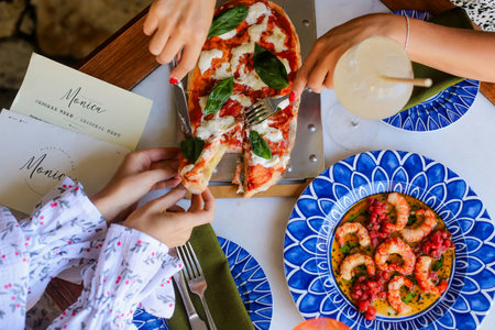 Woman eating pizza with shrimps and basil on the table