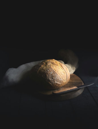 Freshly baked bread on a wooden cutting board on a black background