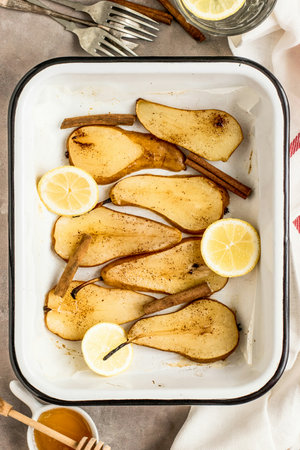 Sliced pear with cinnamon and lemon on a baking tray.の写真素材