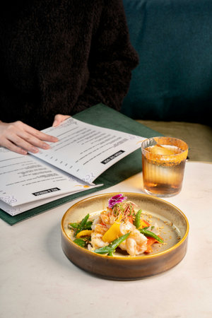 Woman reading a menu in a restaurant. Food and drink concept.
