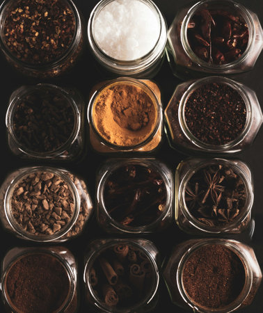 Various spices in glass jars on a dark background. Top view.の写真素材