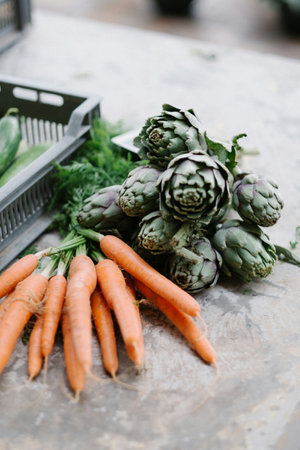 Fresh carrots and artichokes on the table. Selective focus.の写真素材