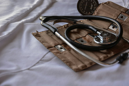 Medical stethoscope on a brown leather case on a white bed.