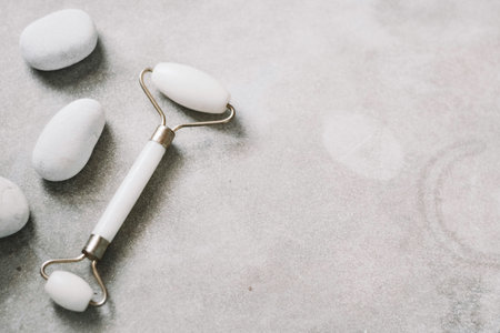 Jade facial massage roller and white stones on grey stone background.の写真素材