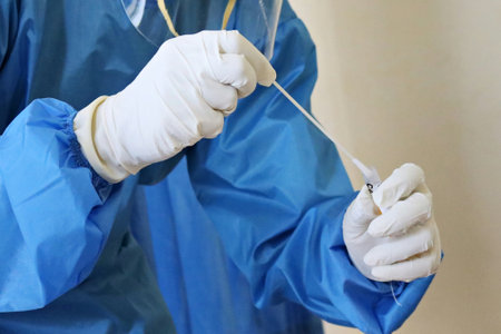 Surgeon in a blue coat and sterile gloves holds a scalpel