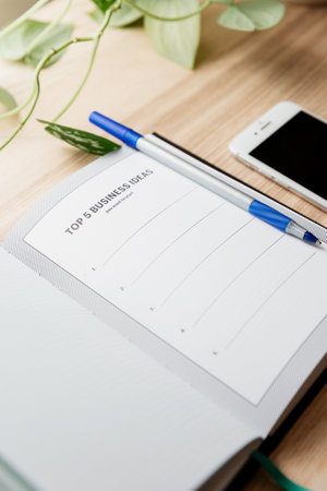 Notebook with pen and mobile phone on wooden table, stock photo