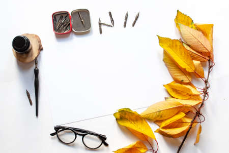 Autumn twig with leaves ,black ink and ink bottle, white sheet mockup and ink pen on a white...