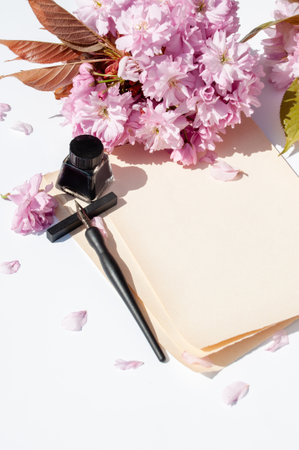 Old ink pen and ink bottle on white background. Vintage calligraphy pen and bottle of ink. Cherry blossom twig with black ink and sheet of paper. Mockupの写真素材