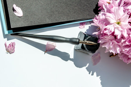 Old ink pen and ink bottle on white background. Vintage calligraphy pen and bottle of ink. Cherry blossom twig with black ink and sheet of paper. Mockupの写真素材