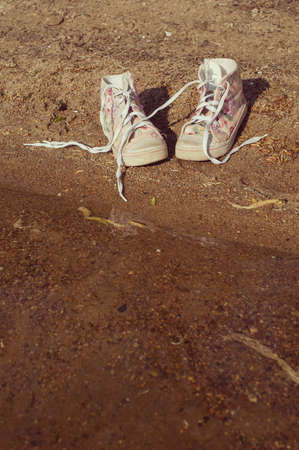 pink gumshoes with long shoelace on the sandの写真素材
