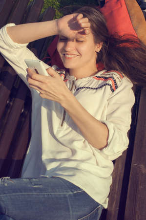 girl lying on the bench and looking at her phone