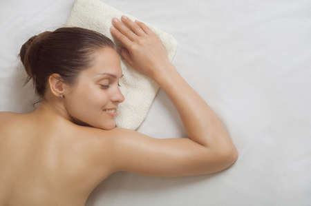 portrait of a top view of girl on a white sheetの写真素材