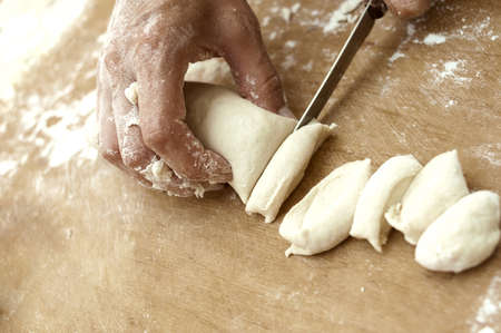 pastry chef cuts dough on a wooden boardの写真素材